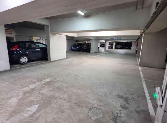 Allée de circulation intérieure d'un parking couvert avec places numérotées.