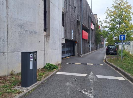 Voie d'accès au parking couvert avec borne de passage et ralentisseur.