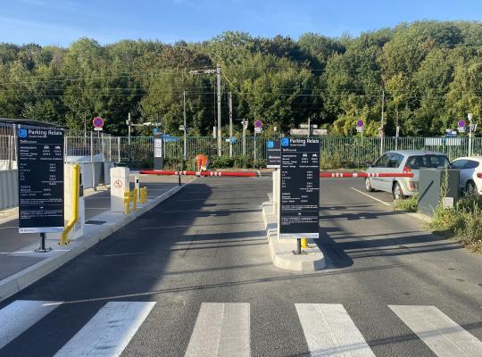 Entrée du parking relais avec barrières automatiques et panneaux tarifaires.
