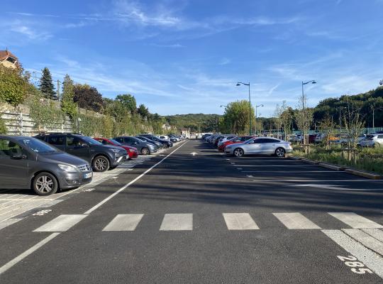Longue allée de circulation bordée d'emplacements dans un parking extérieur.