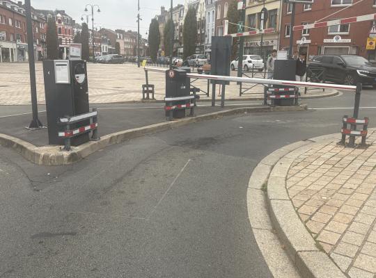 Voie de sortie d'un parking urbain avec barrière automatique et borne.
