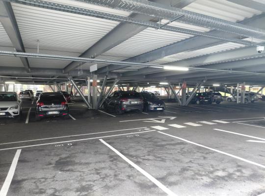 Intérieur d'un parking à étages avec véhicules garés sur des emplacements.