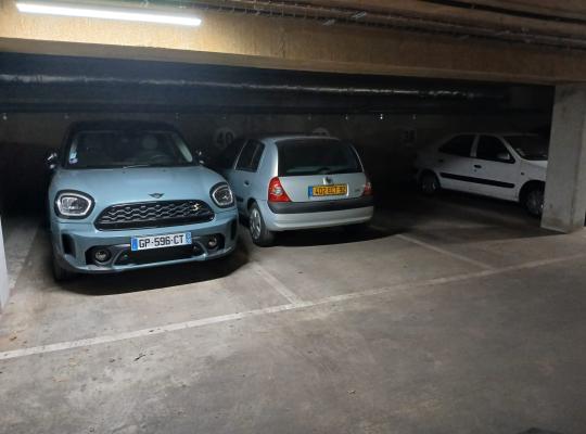 Rangée de véhicules garés sur des emplacements dans un parking souterrain.