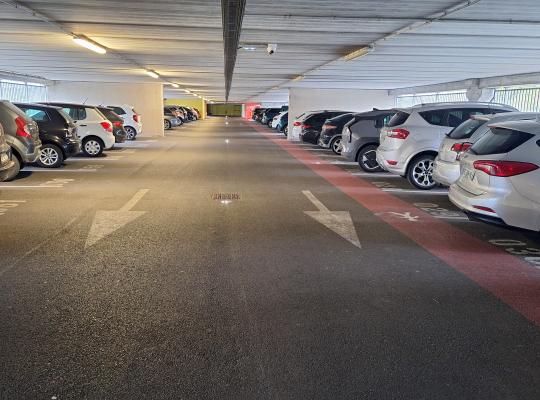 Allée de circulation intérieure avec voitures garées dans un parking couvert.
