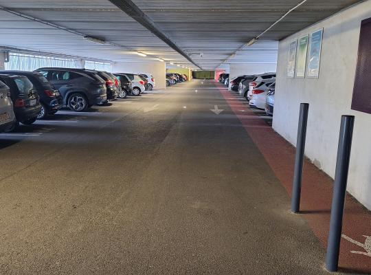 Voie de circulation intérieure longée par un cheminement piéton rouge.