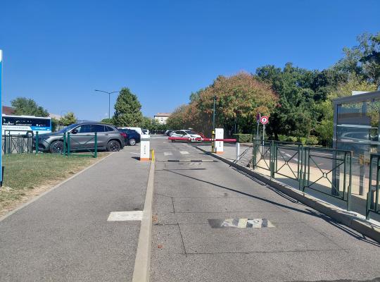 Barrière automatique et bornes à la sortie du parking près d'un abri bus.